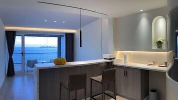 Une cuisine moderne dotée d’un îlot central, de tabourets de bar et offrant une vue sur la mer.