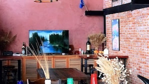 Uma área de bar com televisão, móveis de madeira e plantas decorativas.