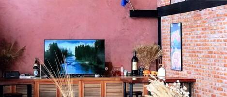 Zona de bar con televisor, muebles de madera y plantas decorativas.