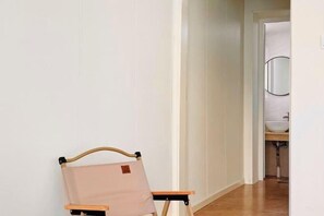 A hallway with a chair and a door leading to a bathroom.