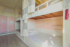 Een slaapkamer met een stapelbed, een houten plafond, een roze garderobe en een witte muur met een plank.