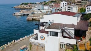 Un edificio costiero con facciata bianca, tetto rosso e vista sul mare.