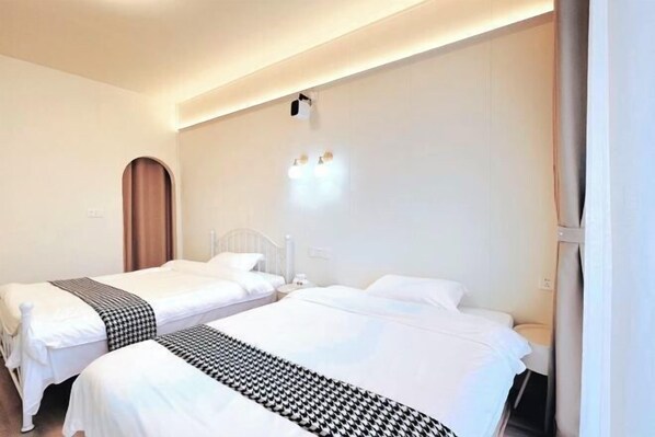 A hotel room with two beds, a wall-mounted light fixture, and a curtain on the right.