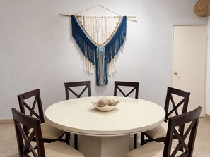 A round dining table with four chairs, a macrame wall hanging, and a decorative bowl on the table. - Casa brisas de Chelem colibrí (Chelem)