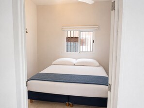 A bedroom with a bed, a window with bars, and a ceiling fan. - Casa brisas de Chelem colibrí (Chelem)