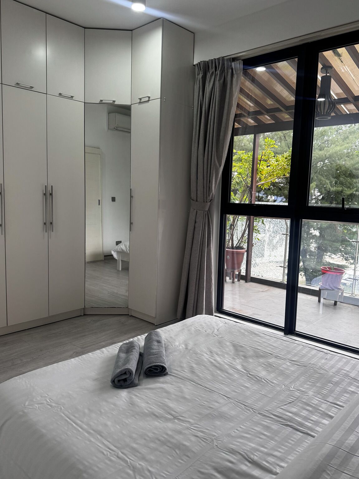 A bedroom with a large bed, a wardrobe, and a window with curtains.