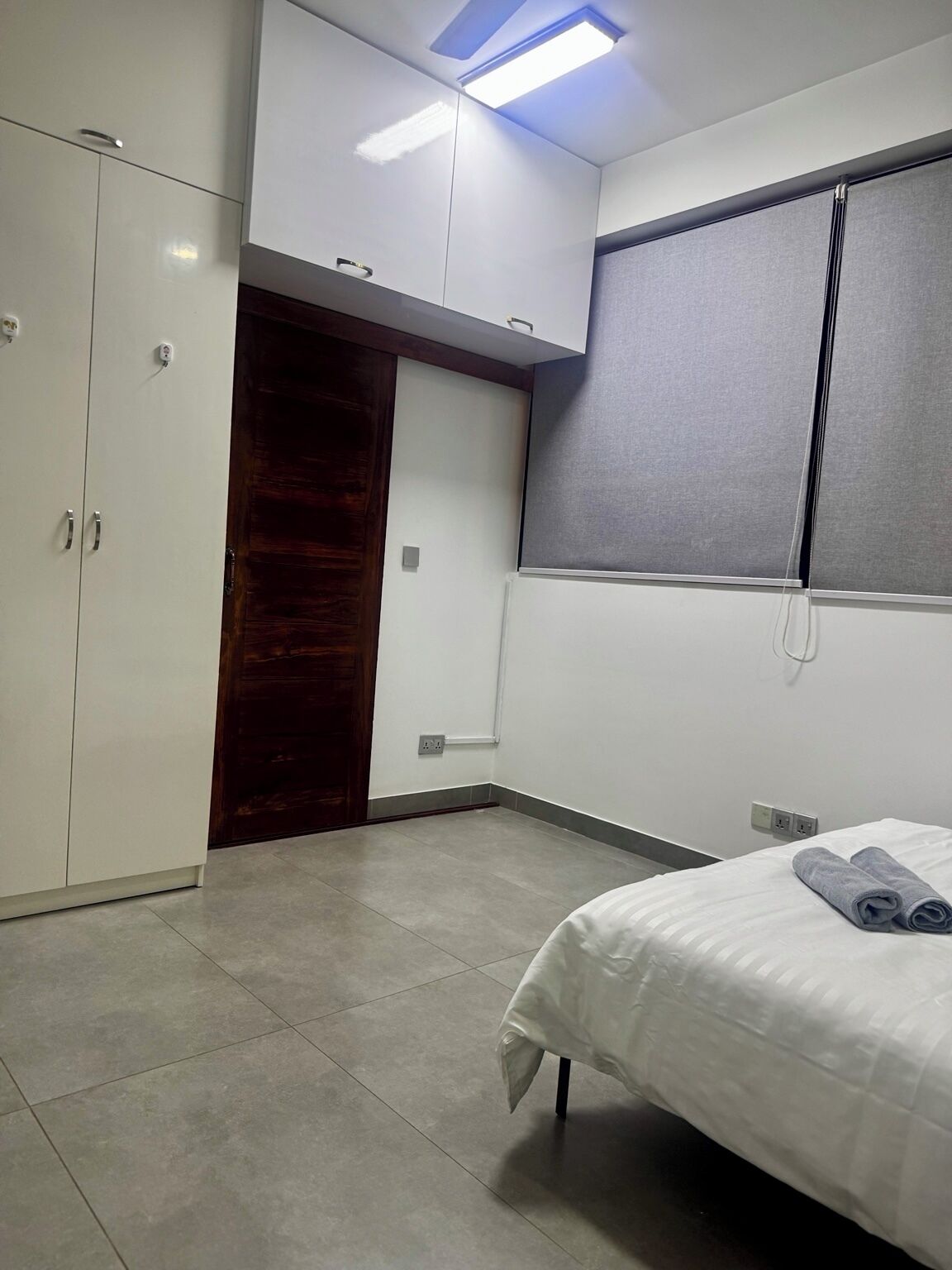 A bedroom with a bed, a wardrobe, a door, and a window.