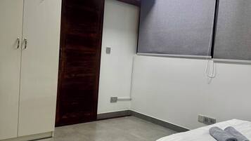 A bedroom with a bed, a wardrobe, a door, and a window.
