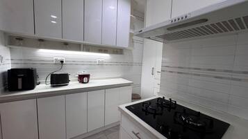 A modern kitchen with white cabinets, a black stove, and a red slow cooker.
