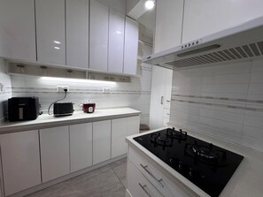 Une cuisine moderne avec des meubles blancs, une cuisinière noire et un autocuiseur rouge.