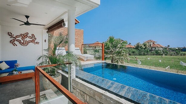 A modern pool area with a clear blue pool, a ceiling fan, and a view of a residential neighborhood.