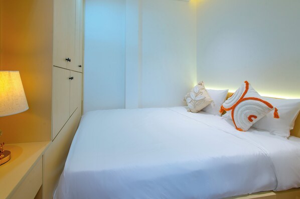 Una habitación de hotel con una cama, una mesita de noche, una lámpara y un armario.