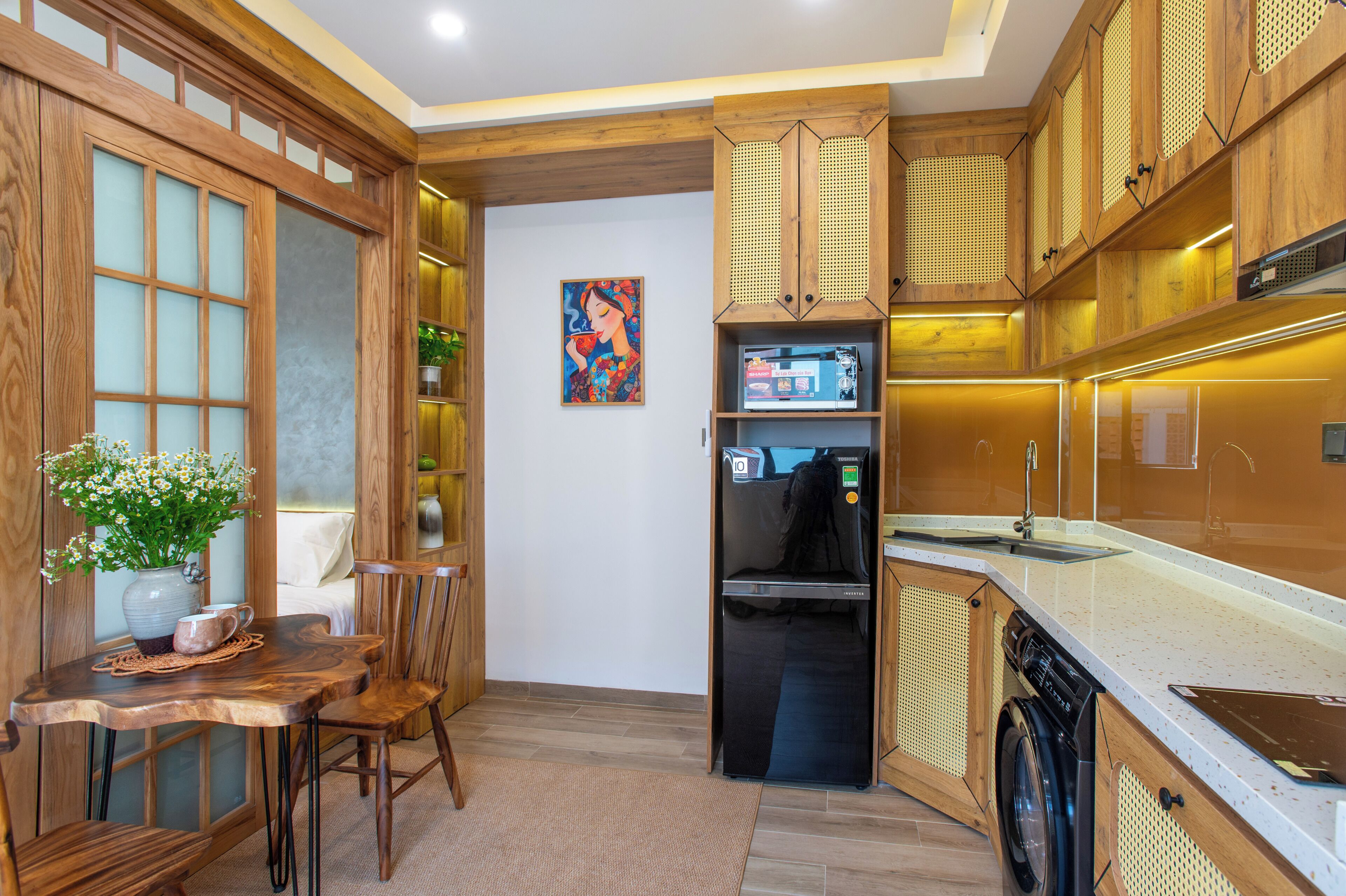 A modern kitchen with wooden cabinetry, a built-in refrigerator, and a dining area with a table and chairs.