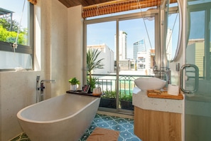 A modern bathroom with a freestanding bathtub, a sink, and a large window offering a city view. - Lavi Residence (Da Nang)
