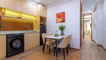 A modern kitchen with a washing machine, a dining table with chairs, and a hallway leading to another room.