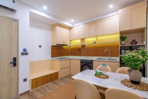 Una cocina compacta con electrodomésticos integrados, un comedor con mesa y sillas, y un pequeño rincón de descanso.