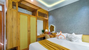 A hotel room with a bed, a wooden wardrobe, a desk with a lamp, and a large mirror. - Lavi Residence (Da Nang)