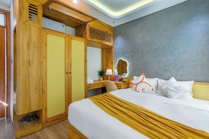 A hotel room with a bed, a wooden wardrobe, a desk with a lamp, and a large mirror. - Lavi Residence (Da Nang)