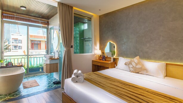A hotel room with a large bed, a bedside table with a lamp, a mirror, and a view of the outside balcony. - Lavi Residence (Da Nang)