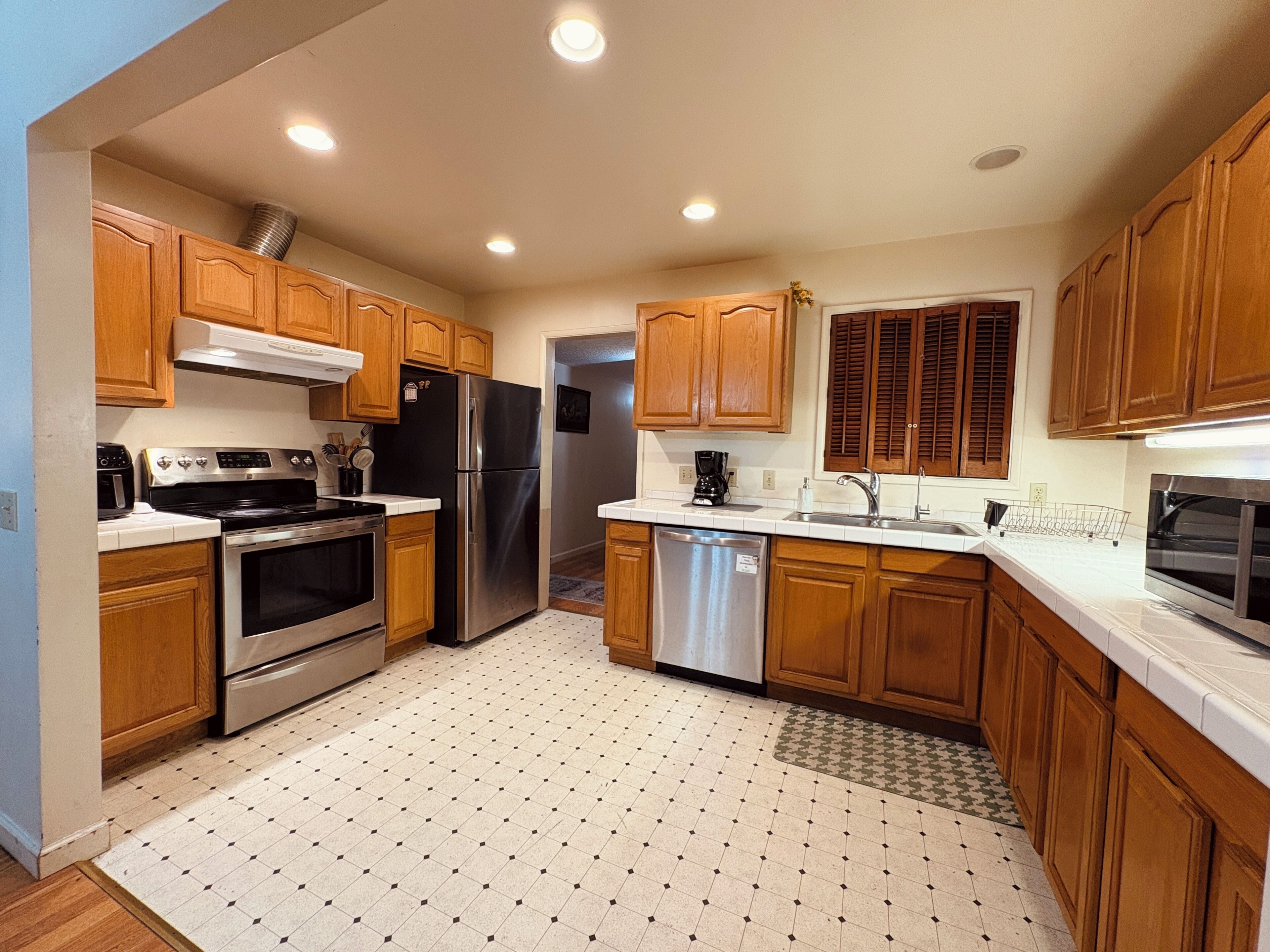 A kitchen with wooden cabinets, stainless steel appliances, and a tiled floor.