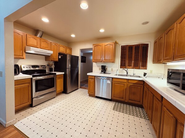 A kitchen with wooden cabinets, stainless steel appliances, and a tiled floor.