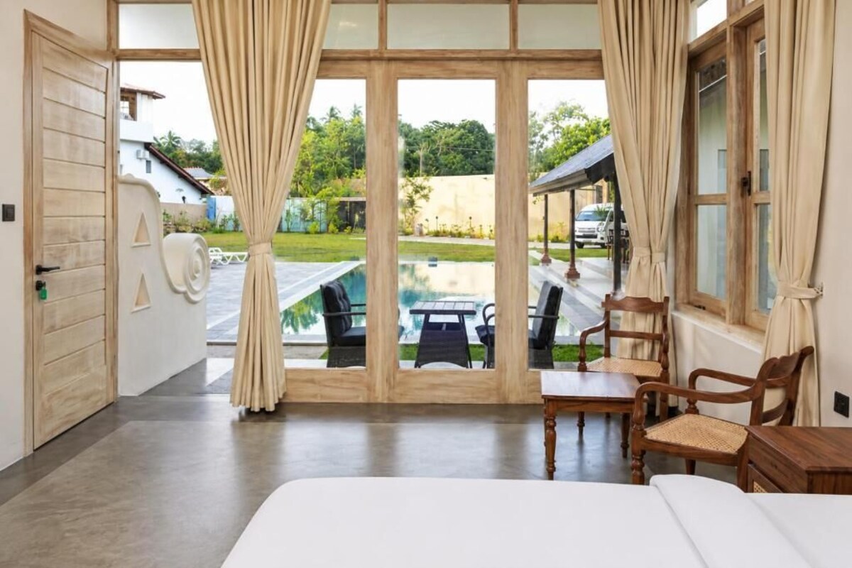 Una habitación con cama, una mesa de comedor y sillas, vistas a una piscina y una puerta que da al exterior.