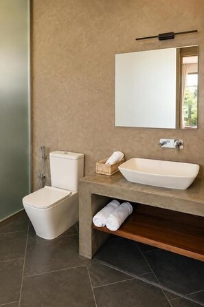 Un baño con inodoro, lavamanos, espejo y toallero.