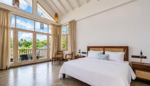 A spacious bedroom with a large bed, a wooden headboard, and a view of a lush garden through large windows. - The Oceans Edge (Dodanduwa)