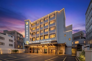 A modern hotel building with a prominent entrance and a parking lot in front.