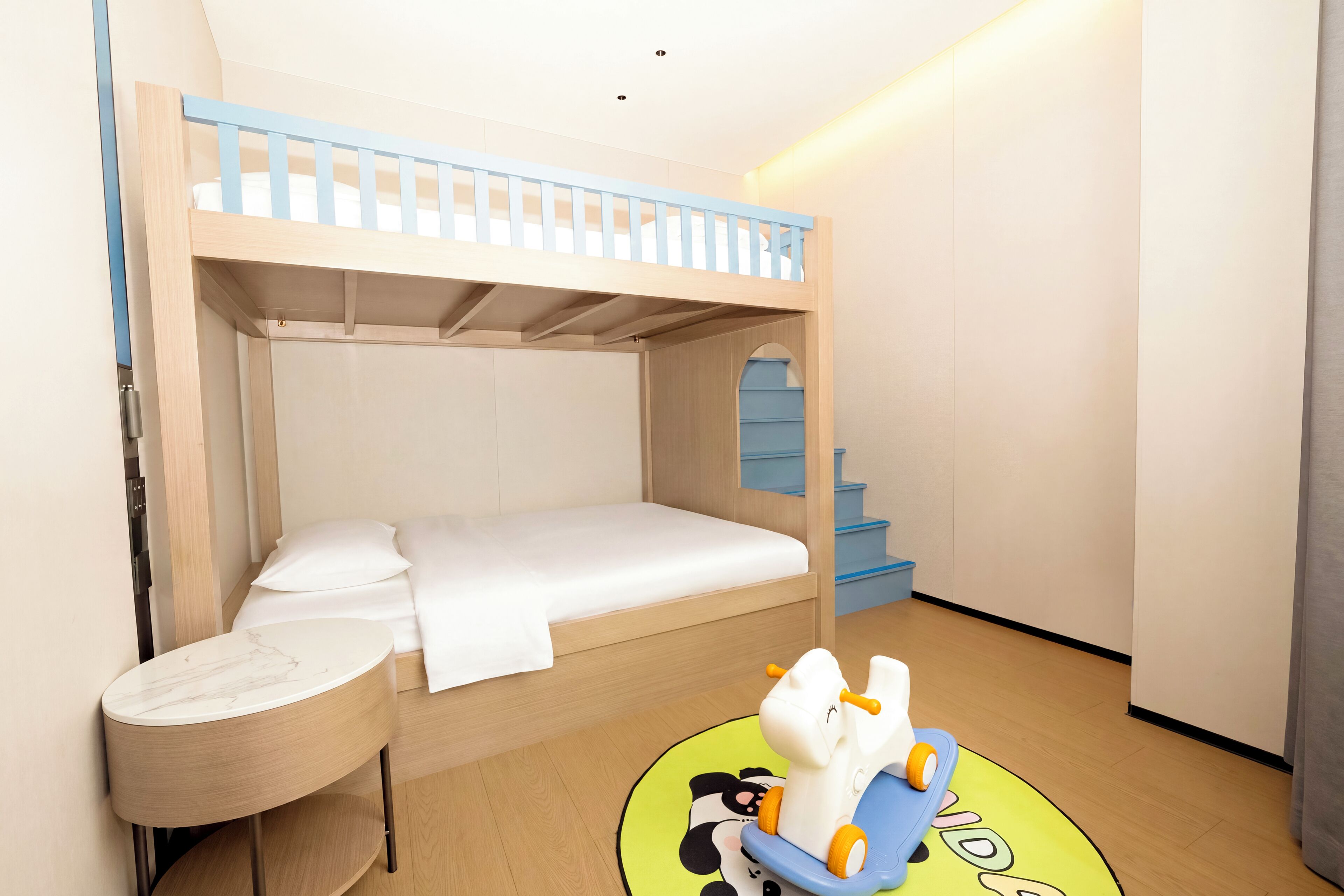 A bunk bed room with a small table and a toy horse.
