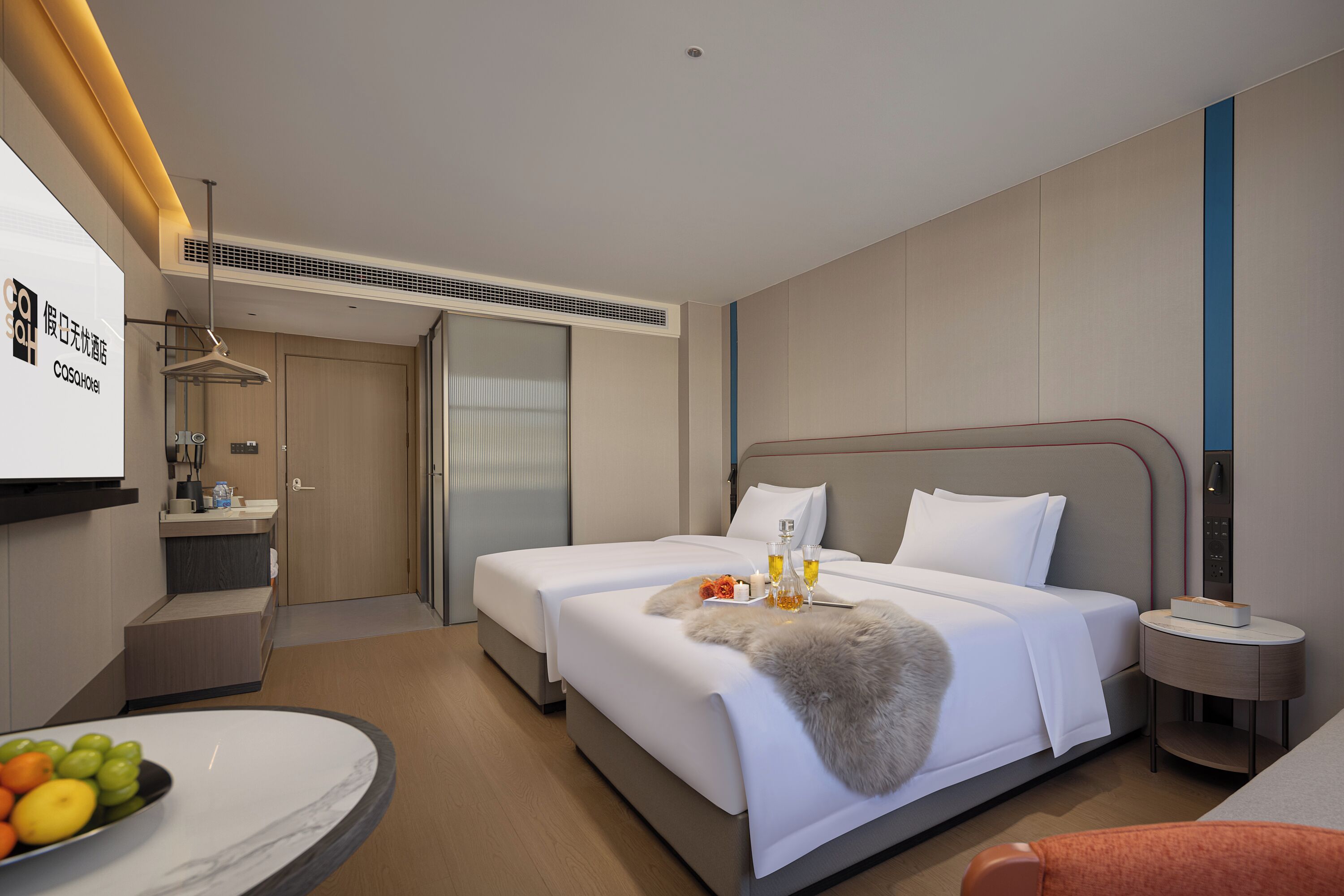 A hotel room with a bed, bedside table, and a desk with a chair.