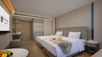 A hotel room with a bed, bedside table, and a desk with a chair.