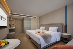 A hotel room with a bed, bedside table, and a desk with a chair.