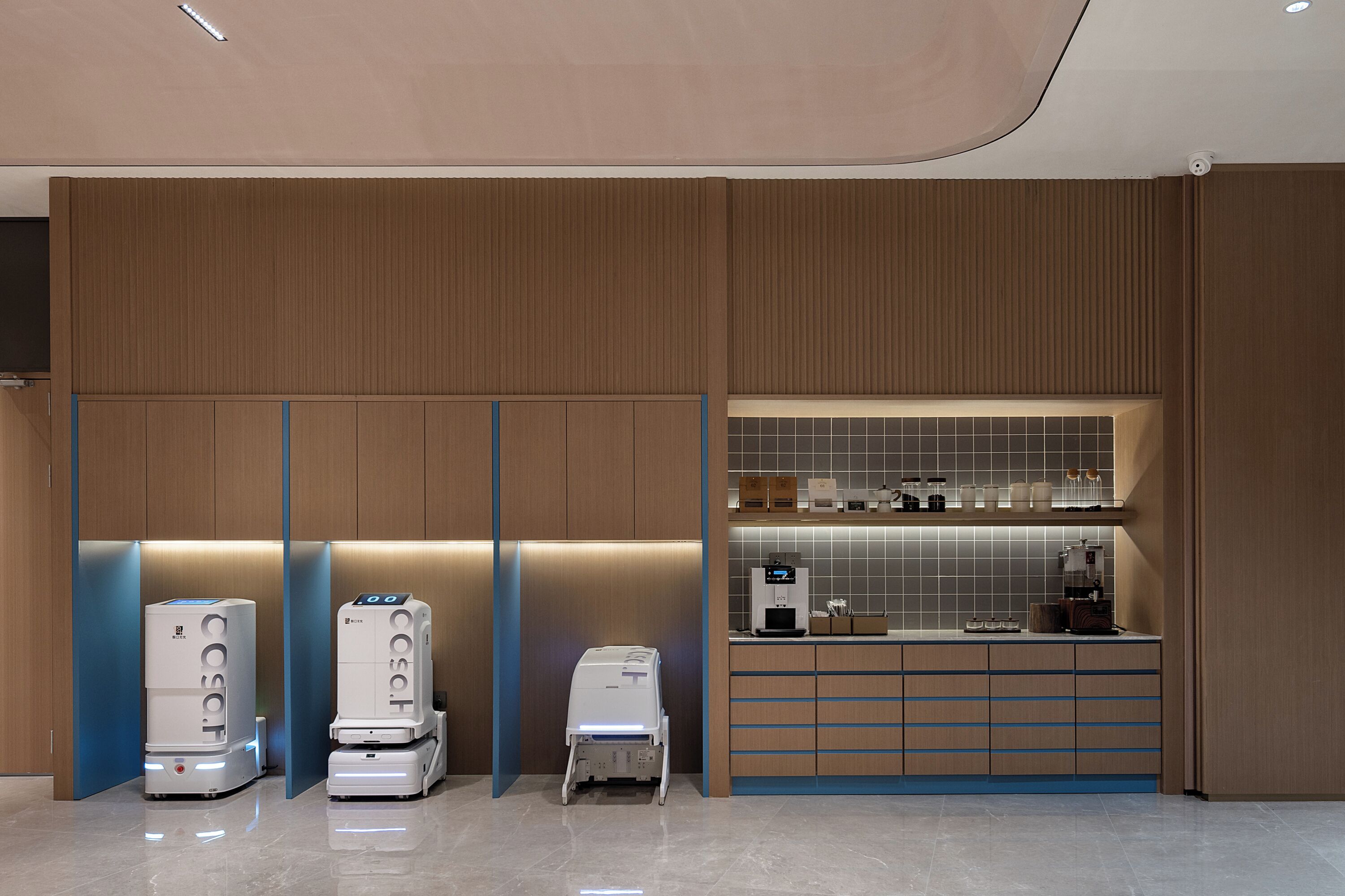 Et moderne receptionsområde med træpaneler, en disk med hårde hvidevarer og tre selvbetjeningsstandere.