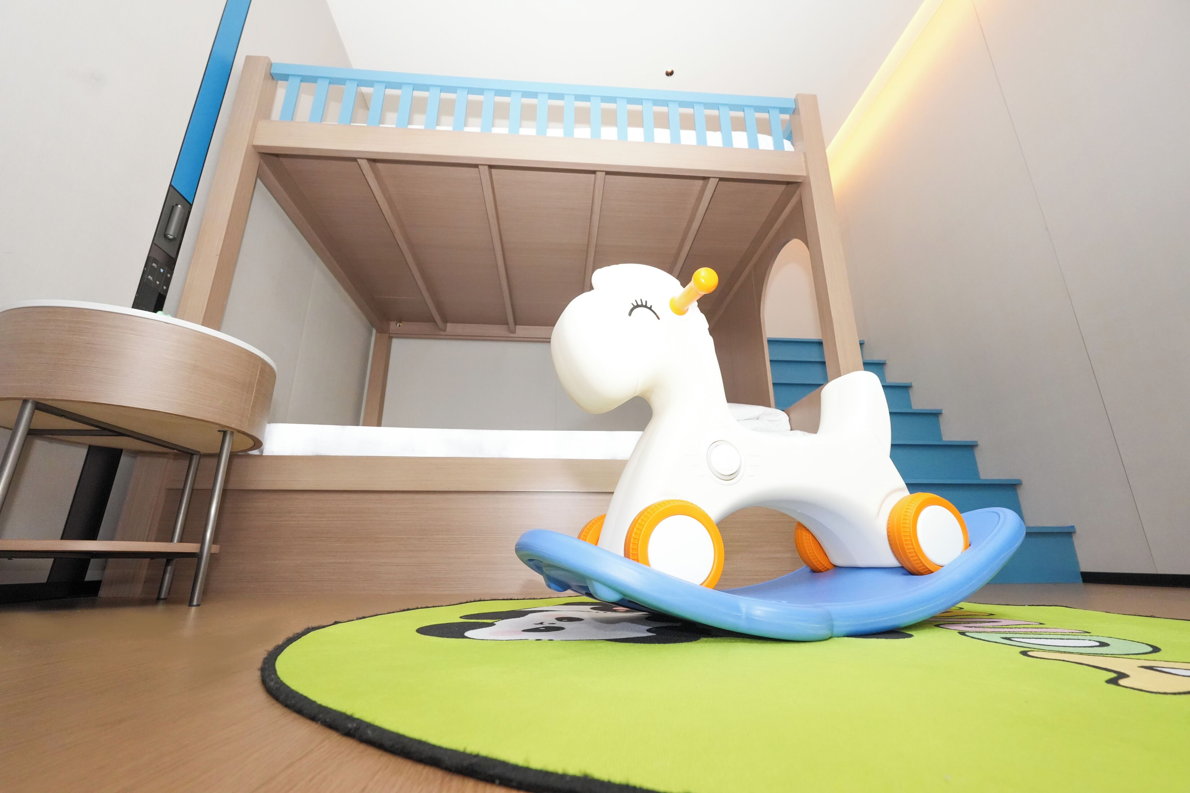A bunk bed with a blue railing and a toy horse on a green mat.