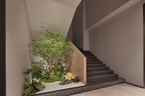 A modern staircase with a wooden handrail and a small indoor garden at the bottom.
