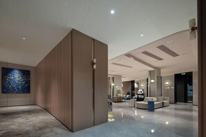 A modern lobby with a wooden partition, a blue abstract painting, and a panda statue.