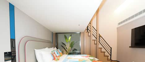 Un dormitorio moderno con cama, mesita de noche y un pequeño escritorio.