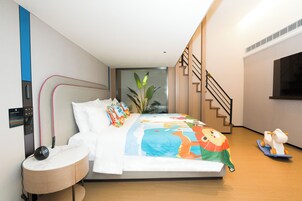 A modern bedroom with a bed, bedside table, and a small desk.