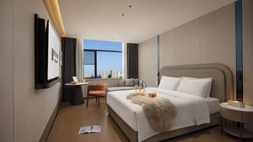 Una habitación de hotel moderna con una cama grande, un escritorio y vistas a la ciudad.