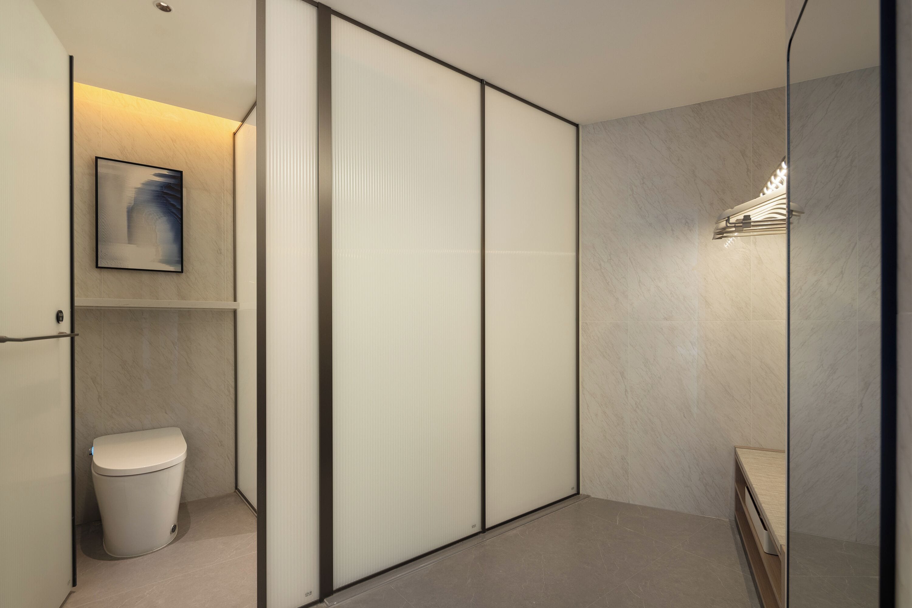 A modern bathroom with a toilet, a shower area, and a wall-mounted light fixture.