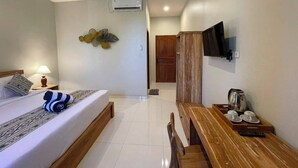 A hotel room with a bed, a wooden bench, a TV mounted on the wall, and an air conditioning unit. - Skyline Sanur (Denpasar)