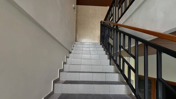 A staircase with a black metal railing and tiled steps. - Skyline Sanur (Denpasar)