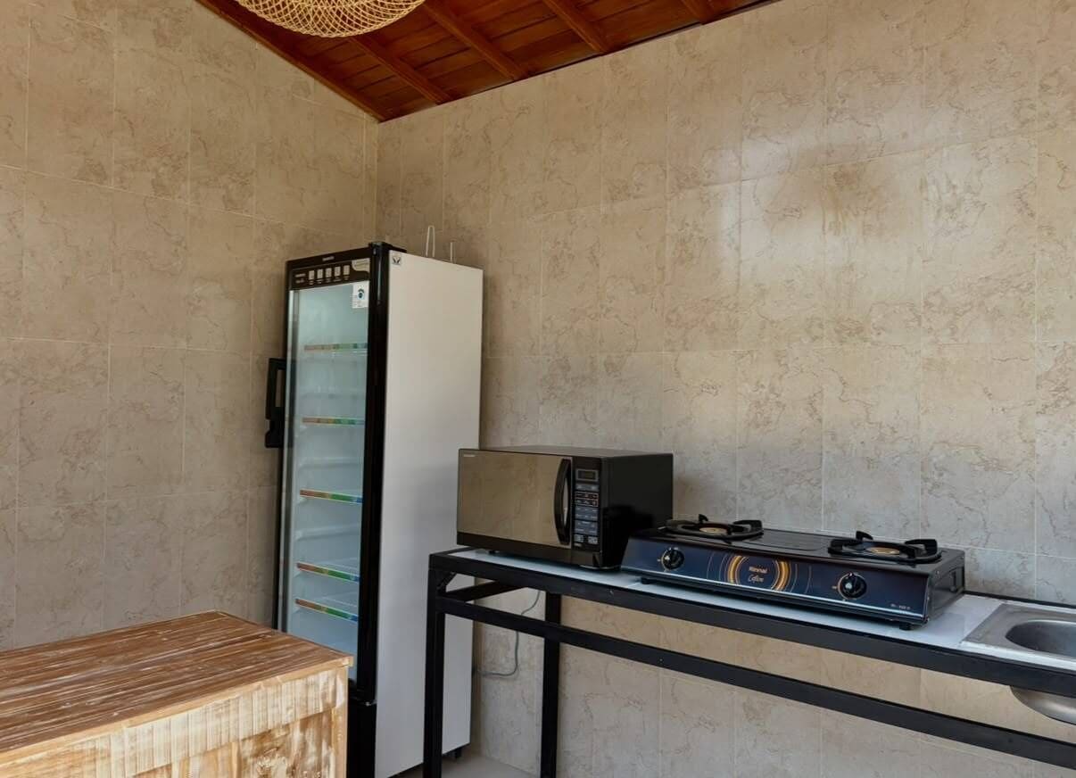 Une petite cuisine équipée d’un réfrigérateur, d’un four à micro-ondes et d’une cuisinière à gaz, le tout installé sur une petite table.