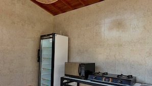 A compact kitchen with a refrigerator, microwave, and gas stove on a small table. - Skyline Sanur (Denpasar)