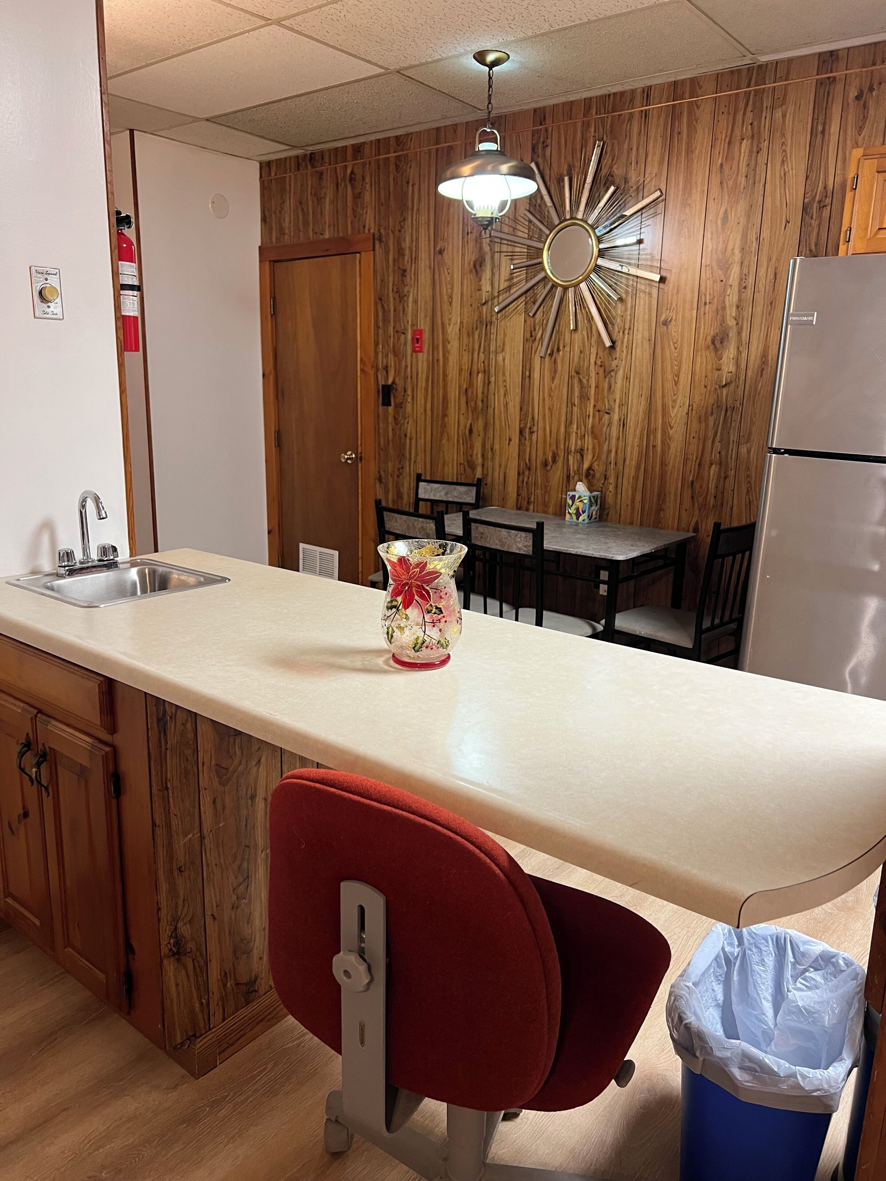 Une cuisine dotée d’un long comptoir, d’un évier, d’un réfrigérateur et d’un coin repas avec des chaises et une table.