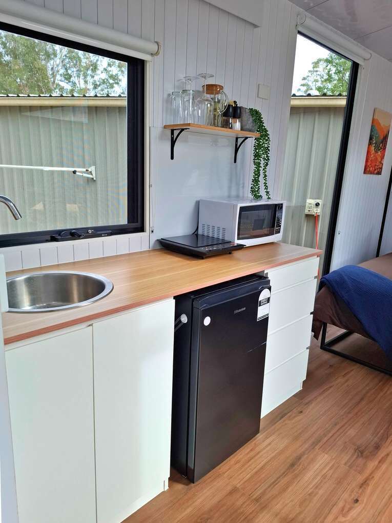 Een kleine keuken met een magnetron, spoelbak en vaatwasser.