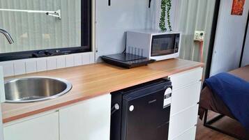 Een kleine keuken met een magnetron, spoelbak en vaatwasser.