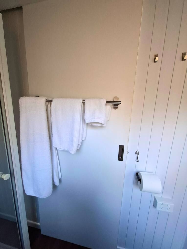 Una puerta con tres toallas blancas colgadas en un perchero.