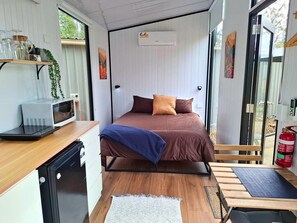 Une petite chambre comprenant un lit, une kitchenette et une fenêtre.